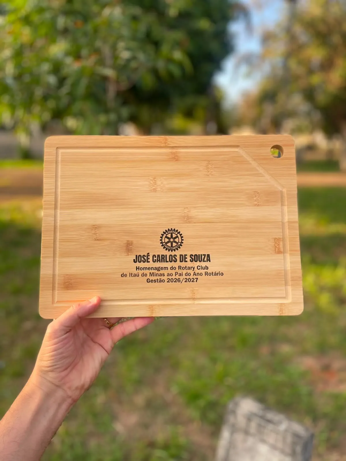 Tábua de bambu com o emblema do Rotary e um nome gravados a laser